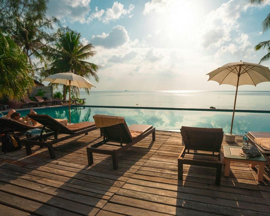 Sun loungers on a wooden deck by a pool, looking out to sea