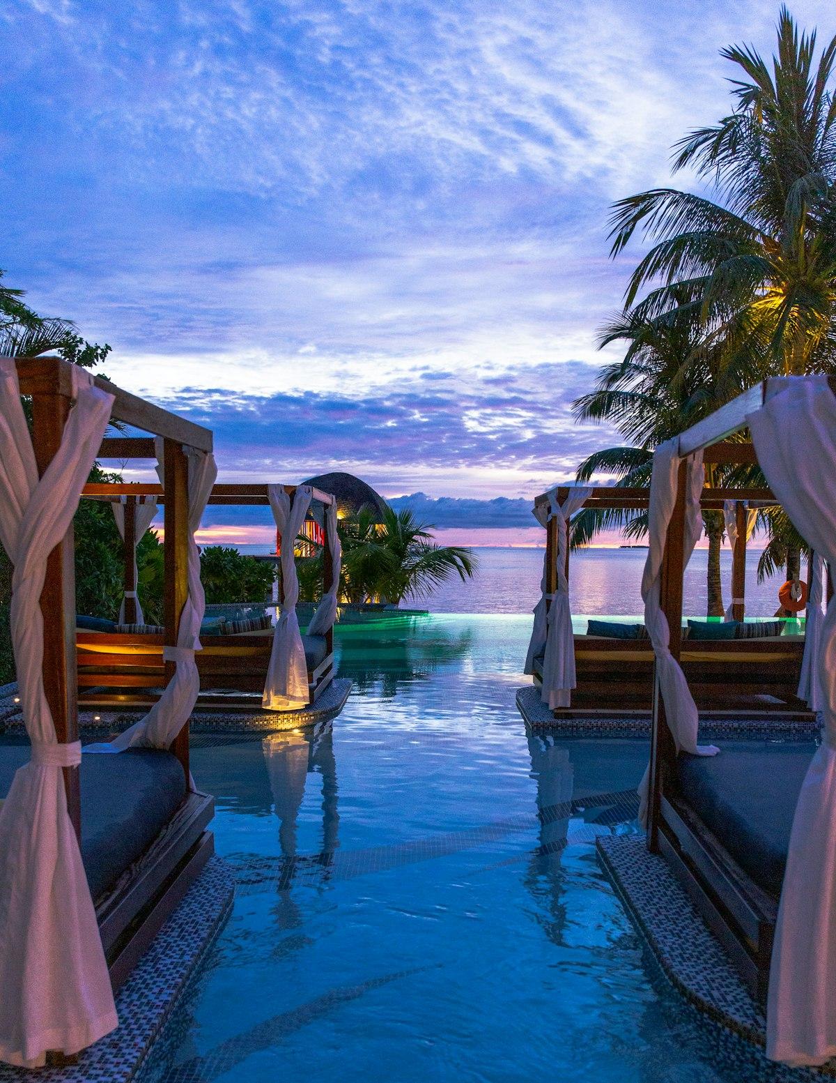 Poolside cabanas with white curtains at sunset