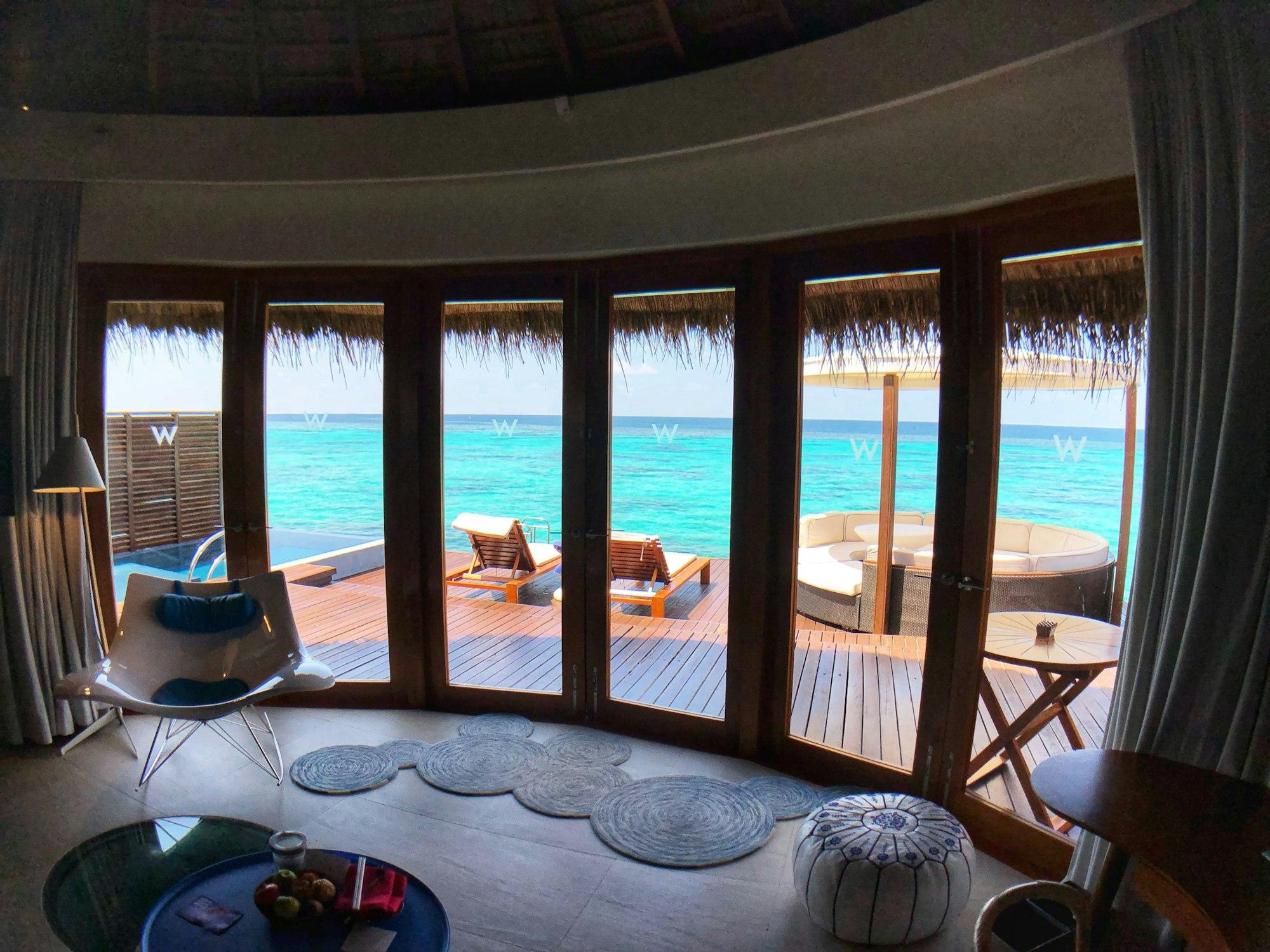 An overwater villa looking out through wide windows to turquoise sea