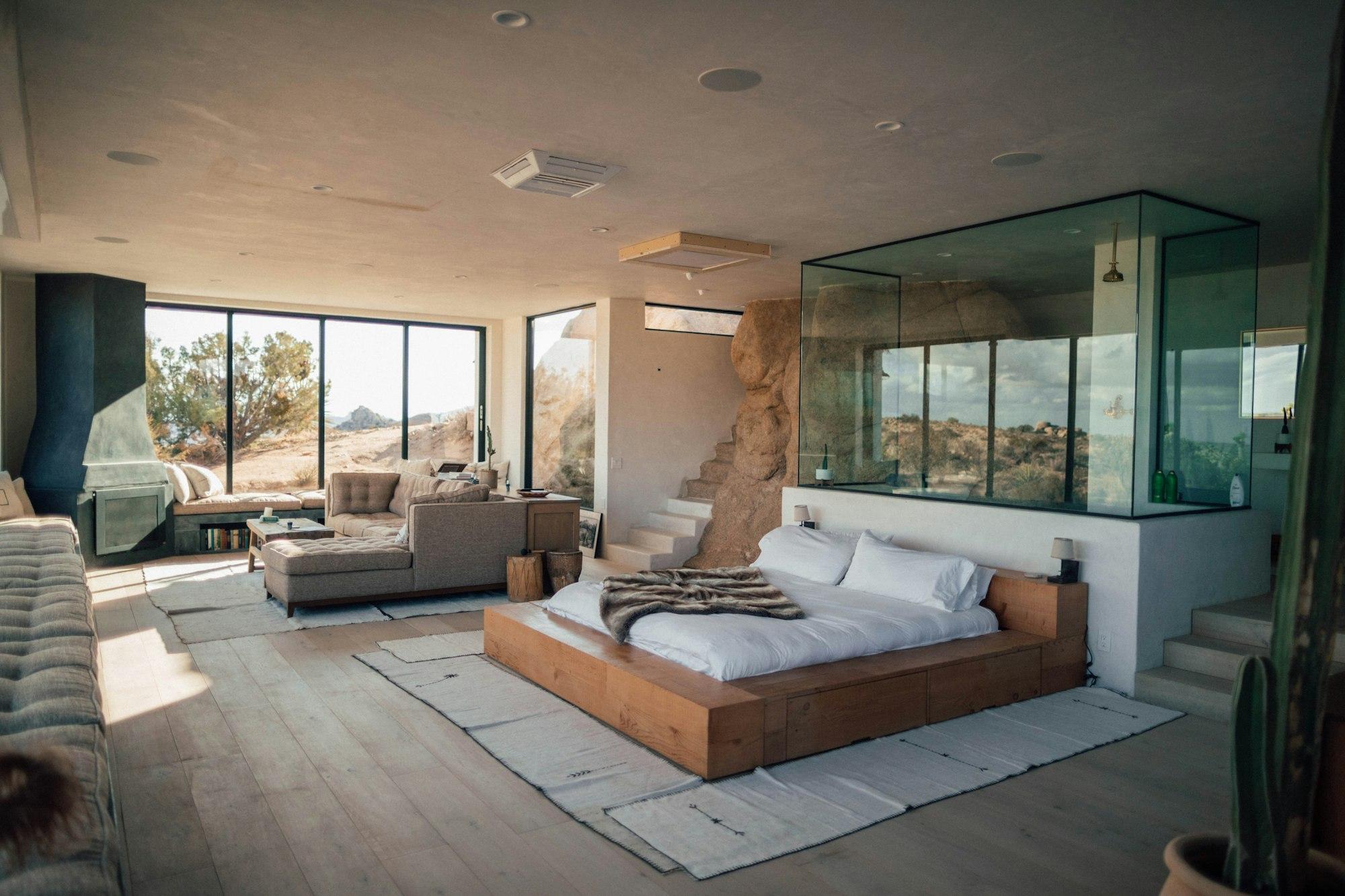 A bright resort bedroom with a low wooden bed and wide windows